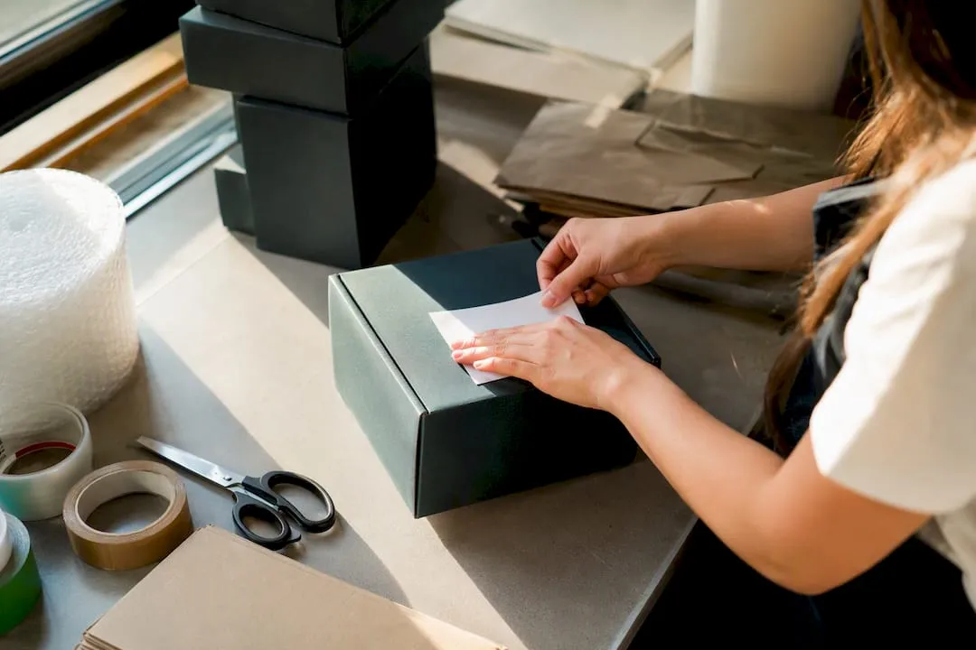 Hands labeling shipping package in ecommerce setting