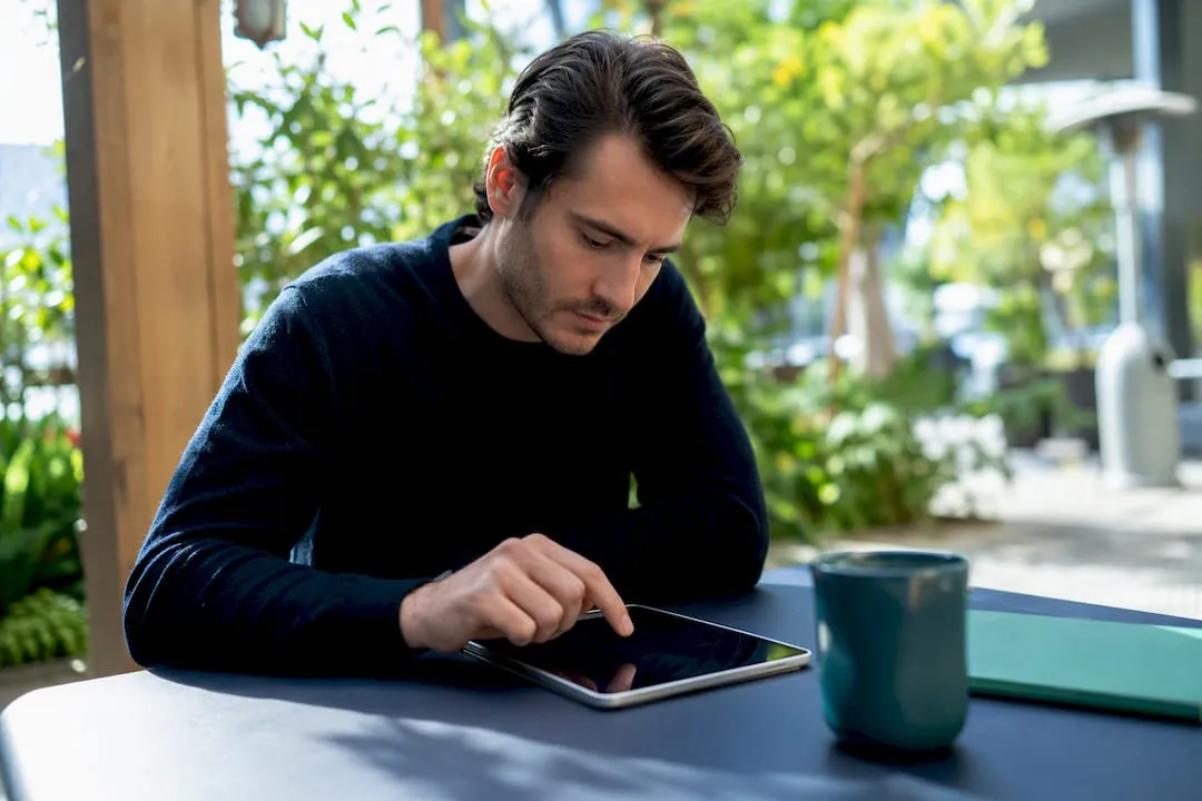 Hand holding tablet on navy desk